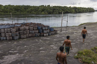Yanomamis ao lado de piaçabas estocadas às margens do rio Padauiri, no Amazonas