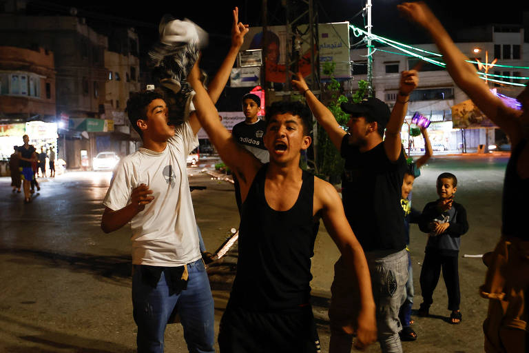 Meninos jovens com braços erguidos em rua à noite