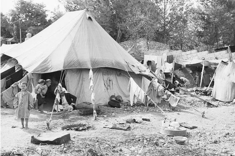 Foto em preto e branco mostra criança em meio a tendas