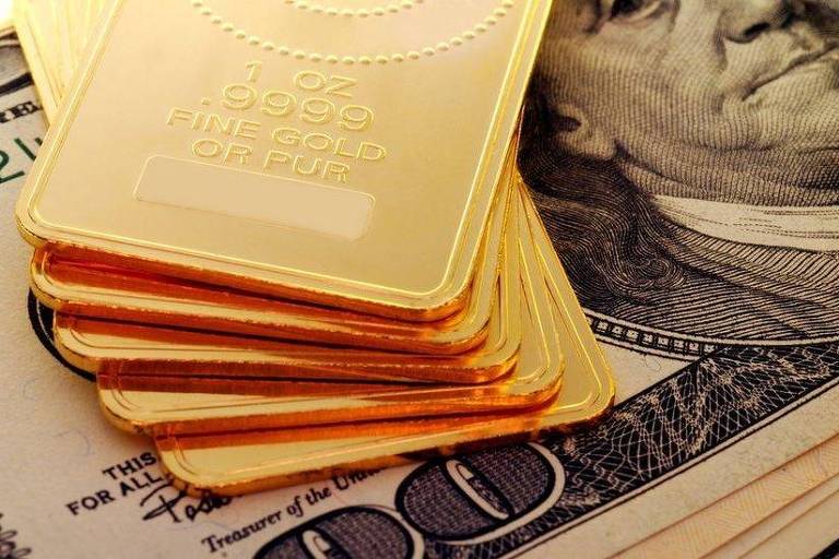 Barras de ouro em cima de notas de dólar