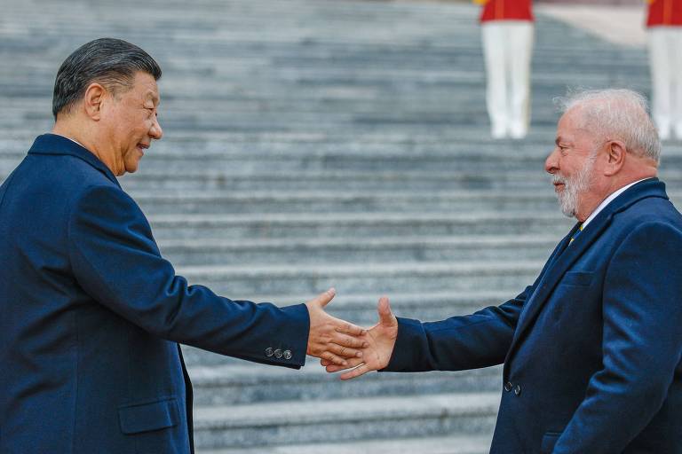 De terno, Xi e Lula esticam os braços para dar um aperto de mãos