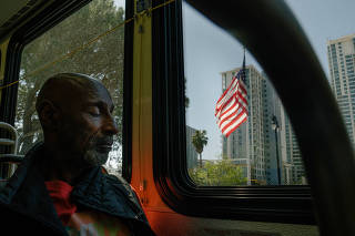 Adbul Curry naps on a public bus while on his way to a church where he has mail sent, in San Diego, April 10, 2023. (Erin Schaff/The New York Times)