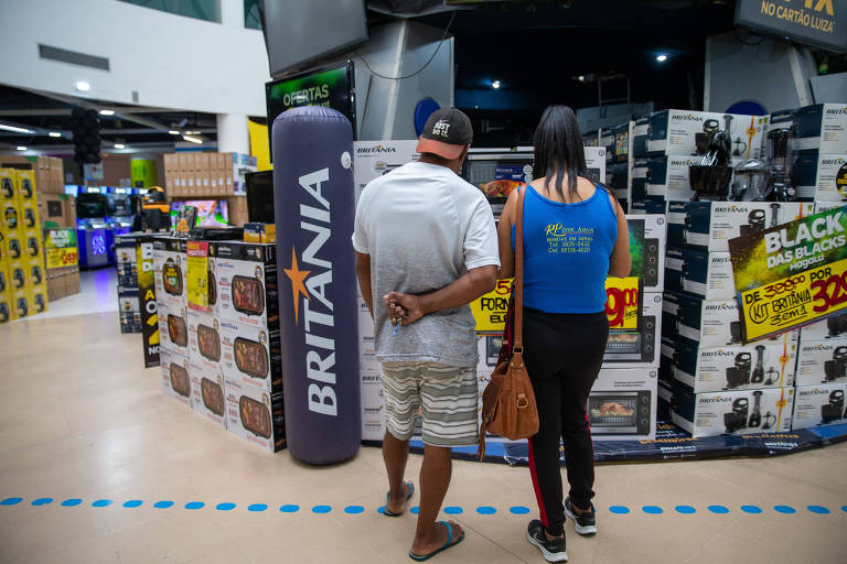 Um casal de consumidores olha para os produtos em promoção da loja Magazine Luiza, da Marginal Tietê.