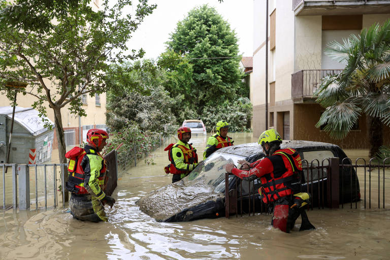 Equipes de emergência atuam em área com carro atingido por enchentes, na região de Emilia-Romagna, na Itália