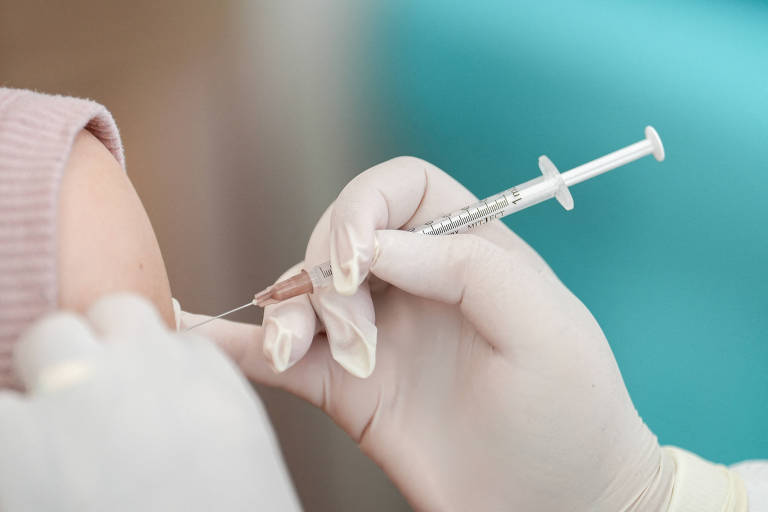profissional de saúde segura seginga para aplicar vacina em braço de mulher branca