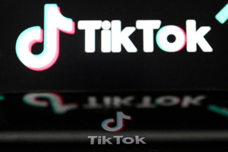 Logo do TikTok em uma tela de celular com o mesmo logo em uma outra tela ao fundo
