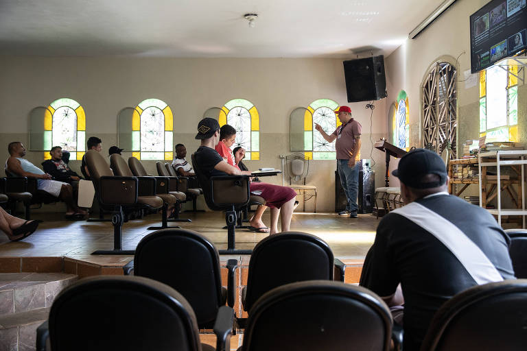 Pacientes sentados em cadeiras assistem em palestra em uma capela da comunidade