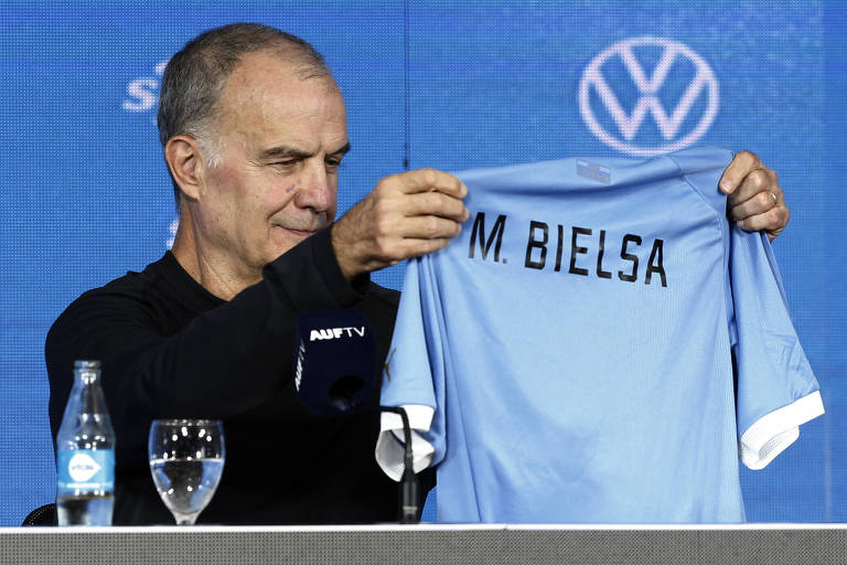 O argentino Marcelo Bielsa em sua apresentação, em Montevidéu, como treinador do Uruguai; ele segura uma camisa da seleção, da cor azul celeste, com a inscrição "M. Bielsa"
