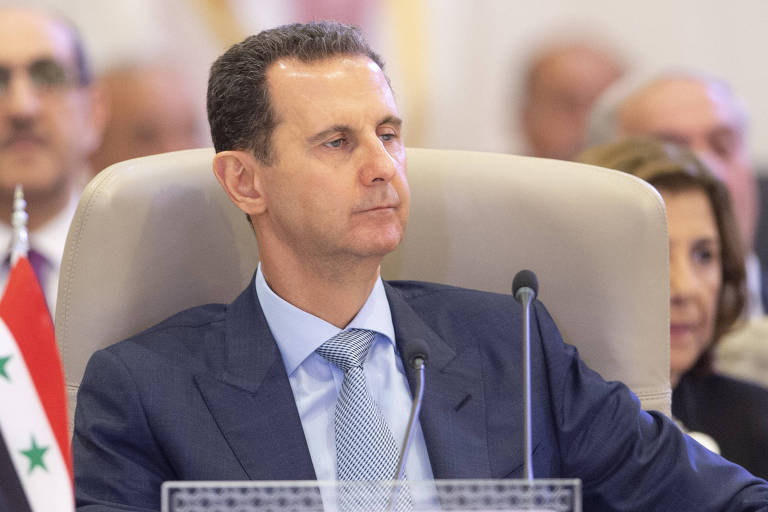 Retrato de Assad sentado a uma mesa