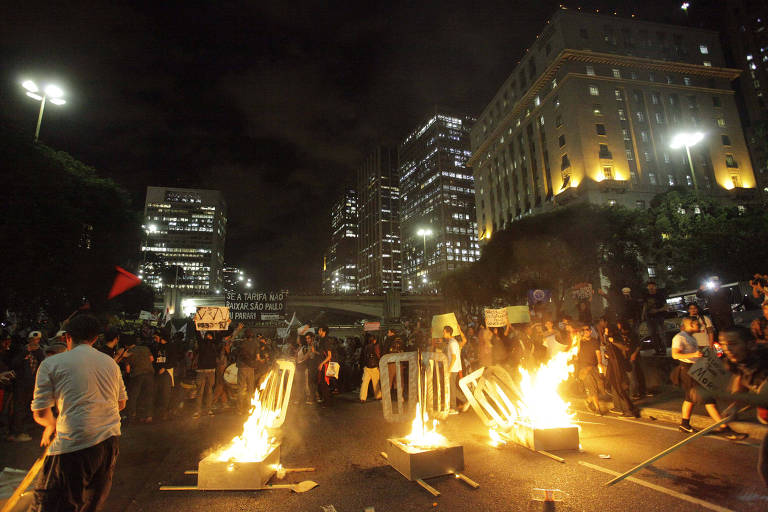 Manifestantes ligados pelo Movimento Passe Livre, ligado a estudantes, ao PSOL e ao PSTU, queimam catracas de papelão na avenida 23 de Maio, em São Paulo