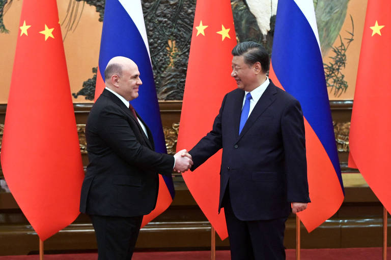 O primeiro-ministro da Rússia, Mikhail Michustin, e o líder da China, Xi Jinping, cumprimentam-se durante reunião no Grande Salão do Povo em Pequim