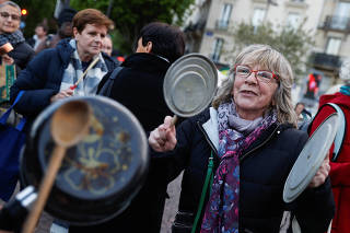 Protesters bang pots in front of a district town hall in Paris