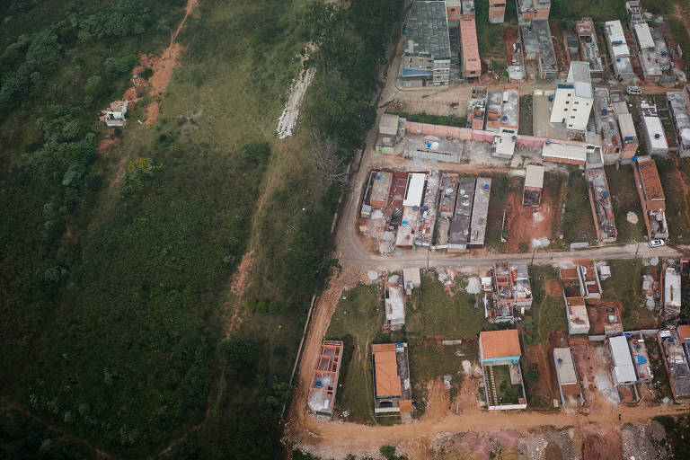 Vista de drone de área verde ao lado de área desmatada com casas construídas