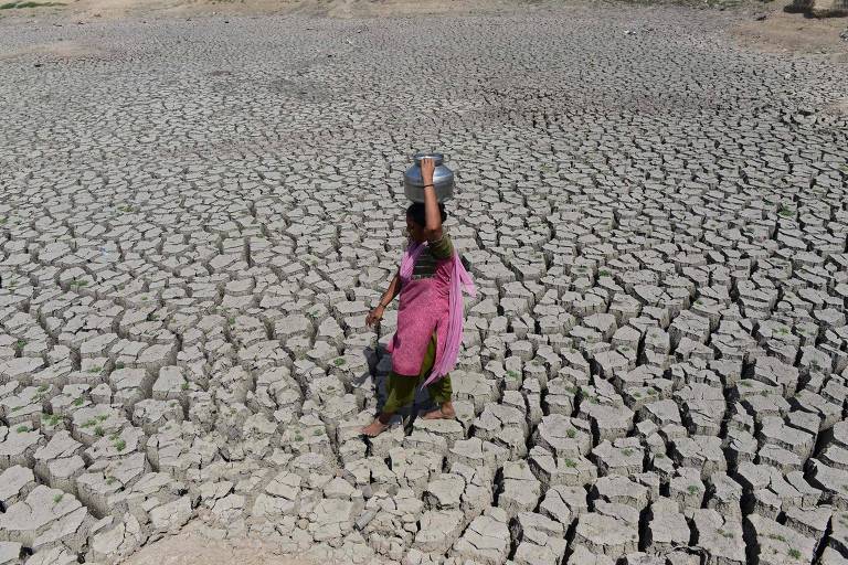 Mulher anda em leito seco de rio na Índia, que vem enfrentando ondas de secas na última década


