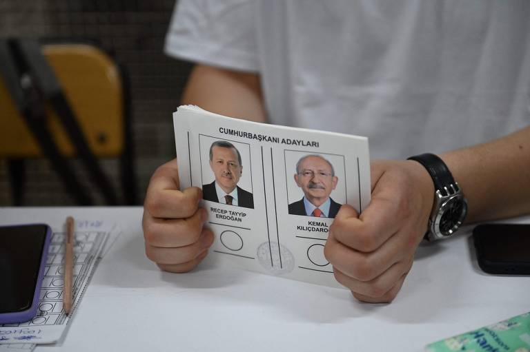 Uma pessoa segura cédulas que mostram os candidatos à Presidência da Turquia em uma seção eleitoral de Istambul