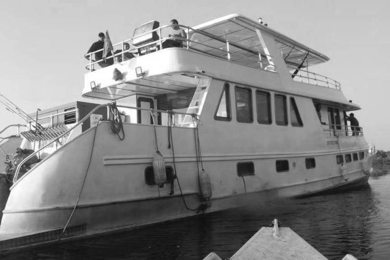 A lancha Arafat, que participou de pescaria ilegal e foi usada em operação policial no rio Abacaxis; trata-se de um barco branco, está num rio de águas marrons