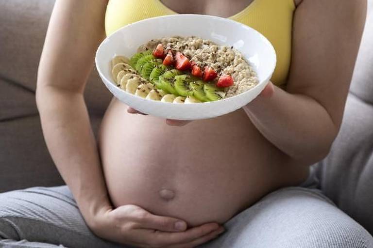 Mulher grávida com prato de frutas