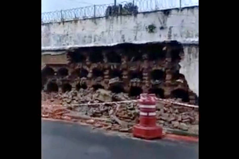 desabamento de muro de cemitério com rua interditada por cone laranja