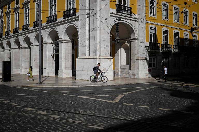 Imagem mostra homem sozinho andando de bicicleta por uma rua vazia do centro de Lisboa