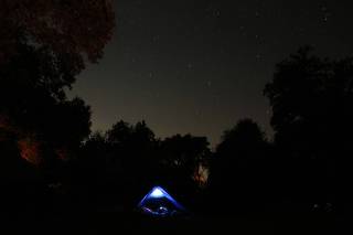 A tent camper is seen under a star-filled night sky in the Southern California mountains near Alpine