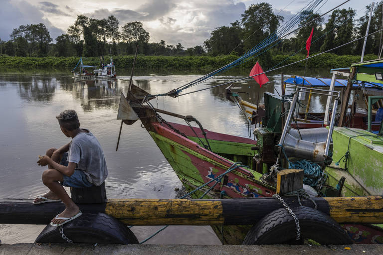Jovem observa uma embarcação navegando pelo rio Caeté, no porto de Bragança, na costa do Pará. O município é um dos principais polos pesqueiros da região.