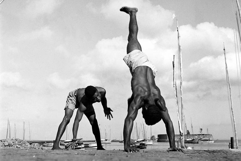 homens lutando capoeira à beira-mar