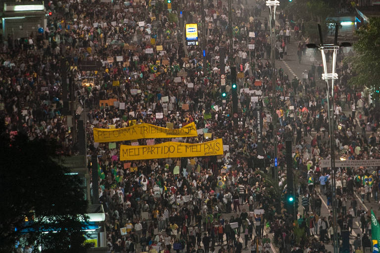 Multidão na avenida Paulista; no centro, duas faixas amarelas, onde se lê demanda por reforma tributária e a frase "meu partido é meu país"