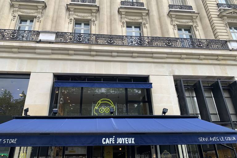 Fachada de antigo edifício em Paris exibe no térreo o toldo azul de um café