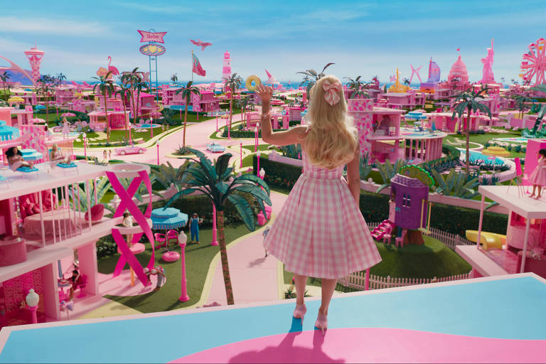 Cena do filme live-action "Barbie". A atriz Margot Robbie, que interpreta a boneca, está de costas, olhando para o mundo da Barbie