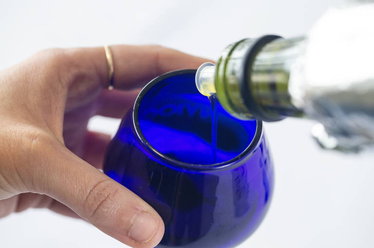 Imagens de garrafas de azeite de oliva em prateleira de supermercado.