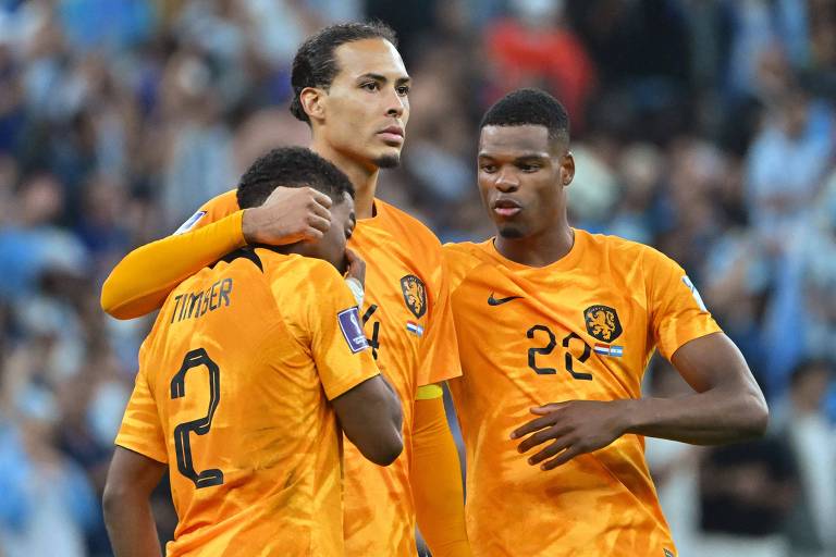 Timber, Van Dijk e Dumfries, da Holanda, vestindo uniforme laranja, consolam-se depois da eliminação diante da Argentina na Copa do Mundo do Qatar 