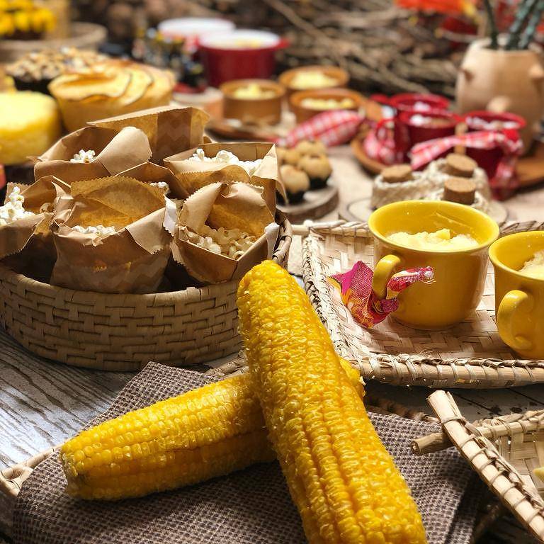 Mesa junina com milho, pipoca e outras comidas típicas servidas em xícaras