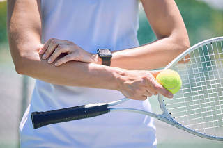 Sports, arm pain and tennis player with a racket and ball standing on a court during for a match. Closeup of a health, strong and professional athlete with equipment touching a medical elbow injury.