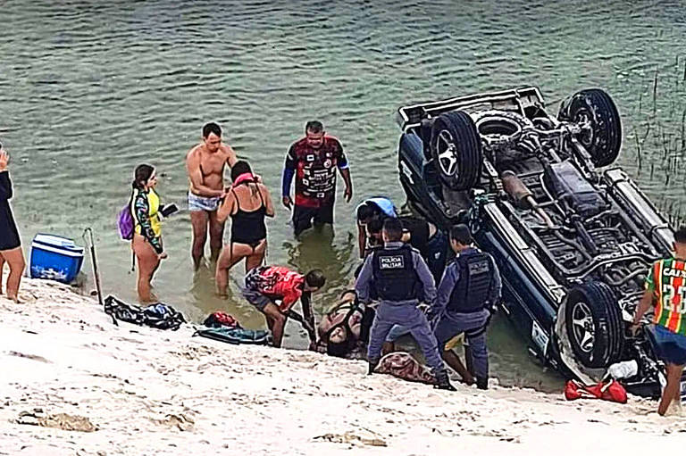 Pessoas de sunga e maiô observam carro capotado dentro de um lago