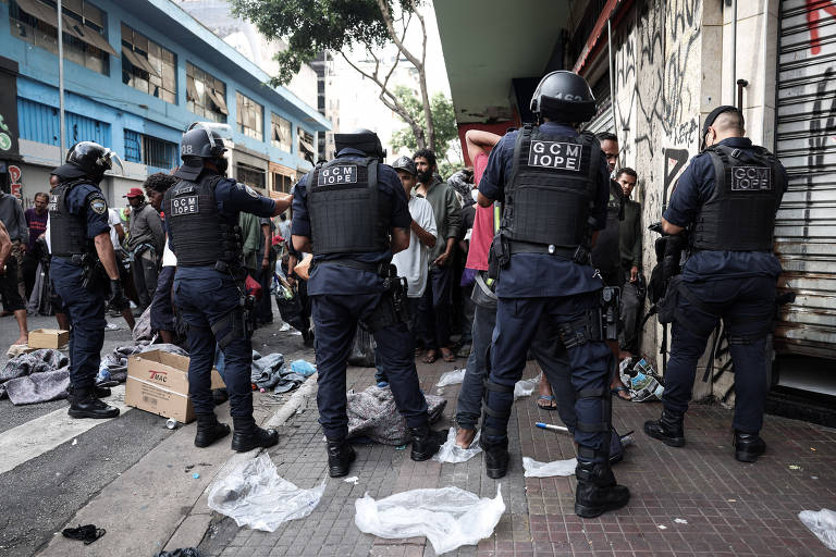 Guardas-civis metropolitanos durante revista aos usuários de droga na rua Guaianases