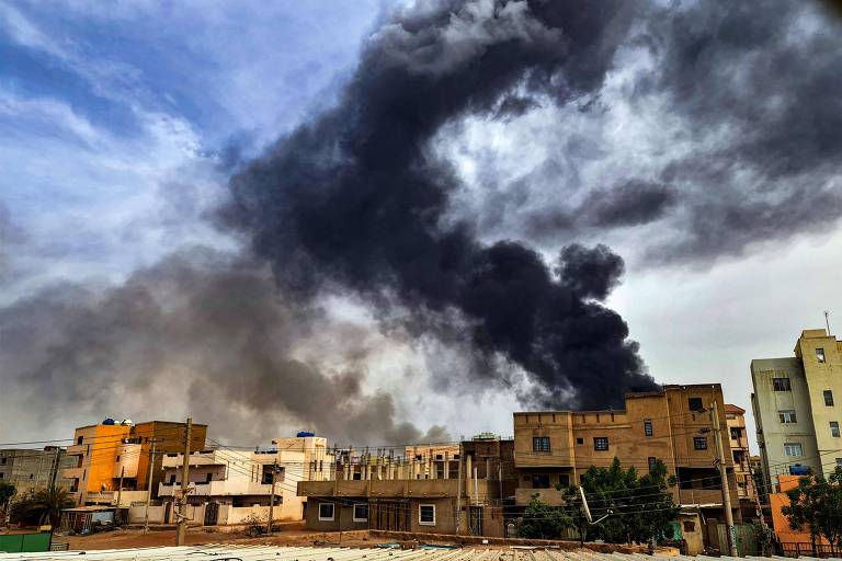Nuvens de fumaça saem de um incêndio em um depósito de madeira no sul de Cartum em meio aos combates em andamento entre o Exército e o grupo paramilitar RSF (Forças de Apoio Rápido)
