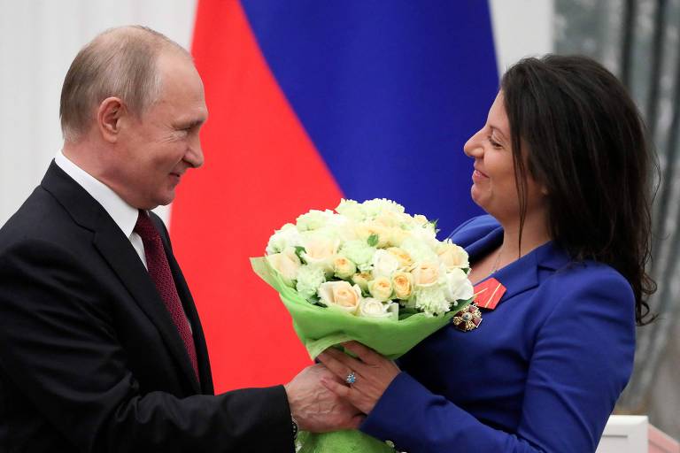 Putin dá flores a Margarita Simonian após ela receber uma condecoração no Kremlin, em 2019
