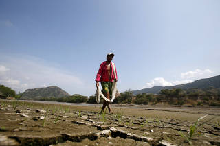 FILE PHOTO: Fisherman Gabriel Barreto walks on the shore of the Magdalena river, the longest and most important river in Colombia, in the city of Honda