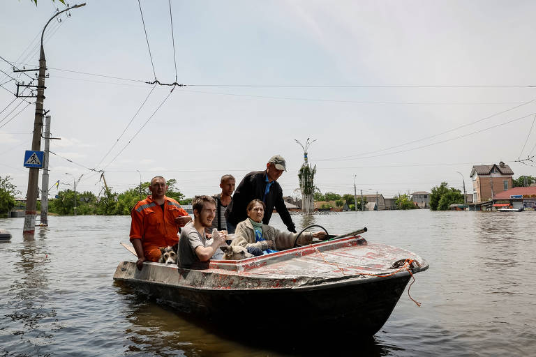 Voluntários ajudam a retirar moradores de área alagada em Kherson, na Ucrânia, que levam junto seus animais de estimação