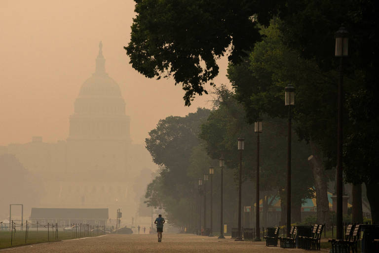 Homem corre próximo ao Capitólio, em Washington, coberta por fumaça alaranjada