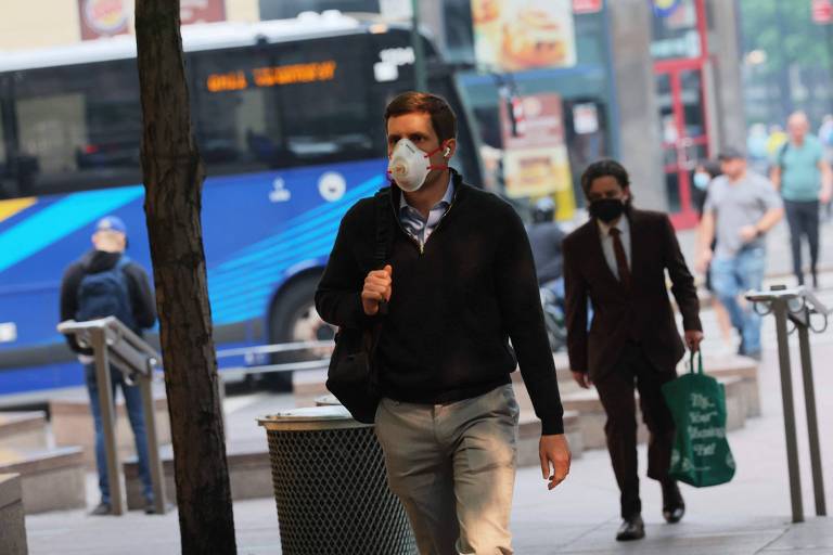 Pessoas caminham pela cidade de Nova York usando máscaras de proteção facial devido à baixa qualidade do ar ocasionada pelos incêndios florestais no Canadá