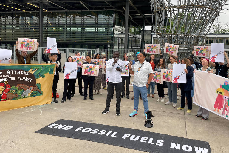manifestantes em protestos com cartazes em que se pede o fim dos combustíveis fósseis