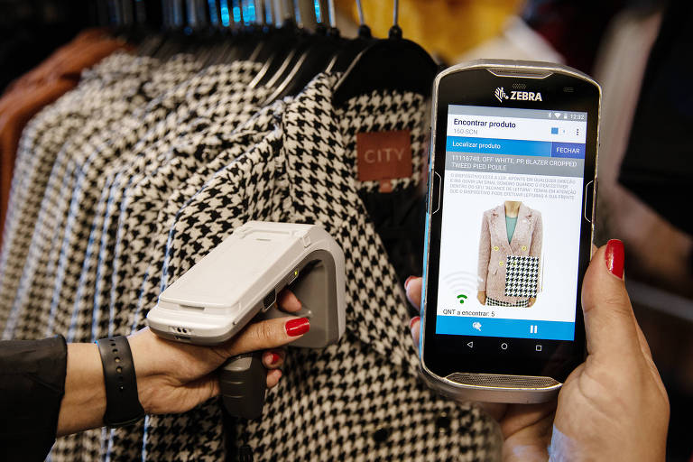 Mulher lê código de roupa com aparelho e celular