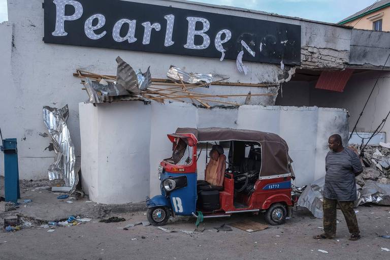 Homem caminha em frente a hotel em Mogadíscio destruído após a invasão de extremistas