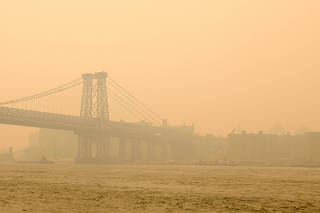 The Williamsburg Bridge is wrapped in haze and smoke caused by wildfires in Canada, in Brooklyn, New York