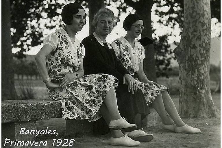 foto antiga em preto e branco mostra três mulheres sentadas em um banco com vestidos