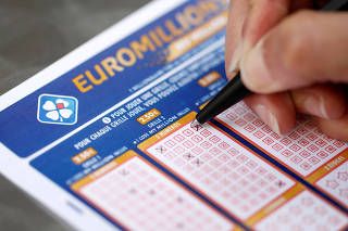 FILE PHOTO: A woman fills out a grid of a lottery ticket for Euro Millions, a lottery game draw, by the French national lottery company Francaise des Jeux (FDJ) in this picture illustration