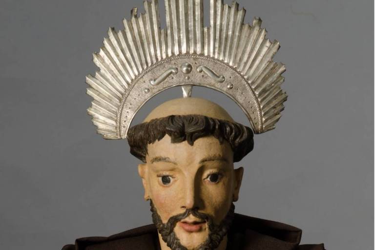 Imagem frontal de São Francisco de Assis Penitente, restaurada, com um resplendor prateado na cabeça, vestimenta marrom e segurando uma caveira.