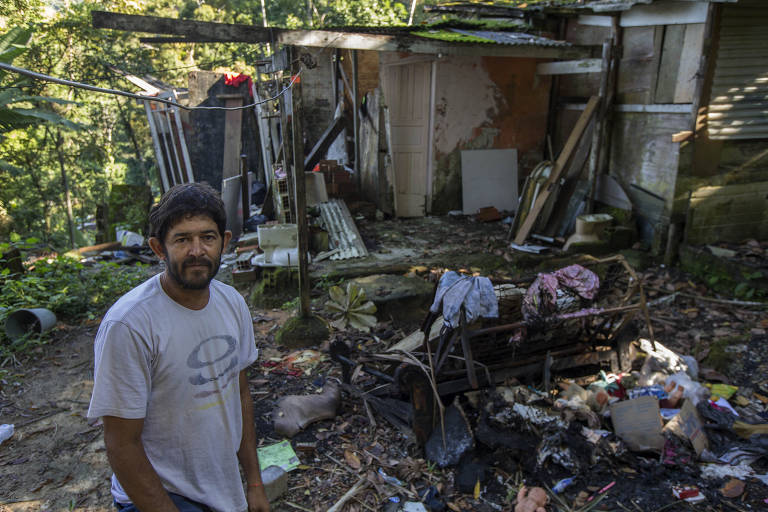 No Morro do Pantal, em Juqueh, Fabio Macedo, 45, posa em frente a casa da filha que caiu parcialmente depois de liberada pela Defesa Civil para ser reocupada