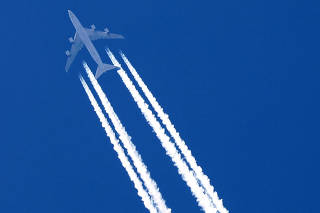 FILE PHOTO: A plane leaves behind contrails as it flies in the sky over Paris